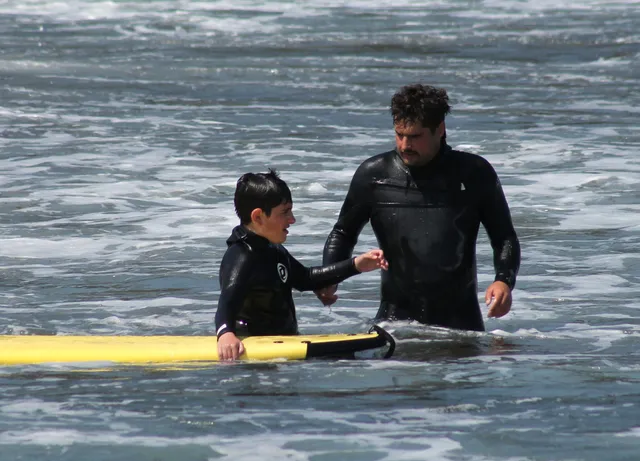 Familia disfrutando de una clase de surf juntos en la playa de Frexulfe