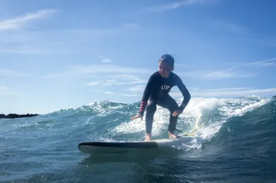 Niños surfeando en una clase en la playa de Frexulfe